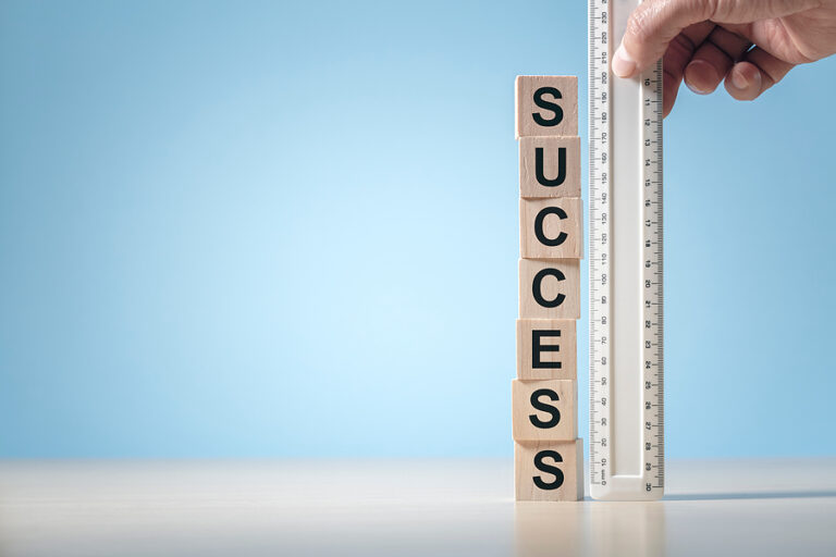 A plastic ruler measure the height of a tower of blocks that spell out "success"