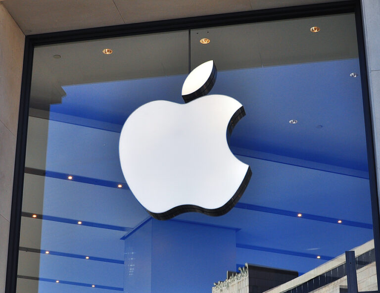 The Apple logo displayed on a glass wall.