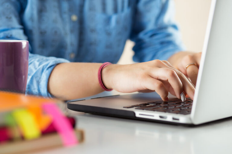 Women typing on a laptop.