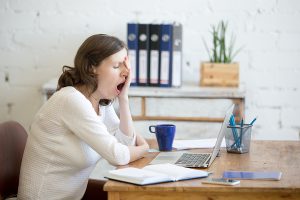 Bored worker yawning at desk, representing a business in a boring industry.