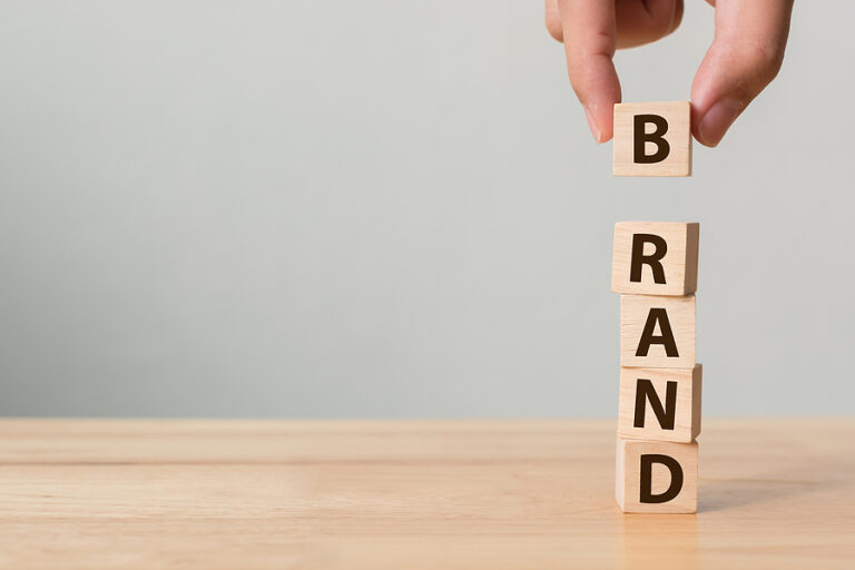 Hand Stacking Wood Cube Blocks With Word "brand" On Them.