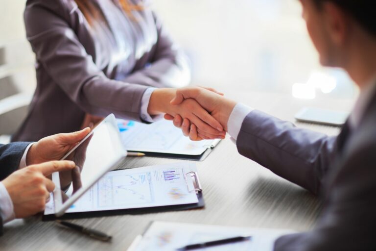 Business people shaking hands across desk.