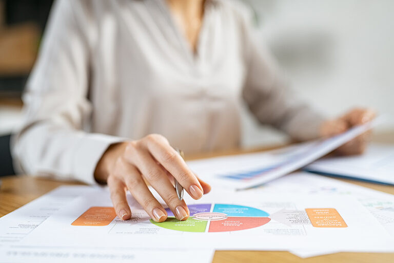 A businesswoman sitting at a desk littered with papers with her finger pointing at a SWOT analysis