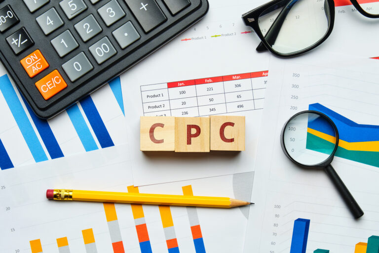 Marketing analytics charts, office supplies, and calculator with CPC wooden blocks in foreground.