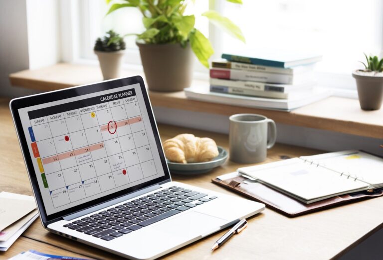 Laptop at casual desk with event planner calendar app open.