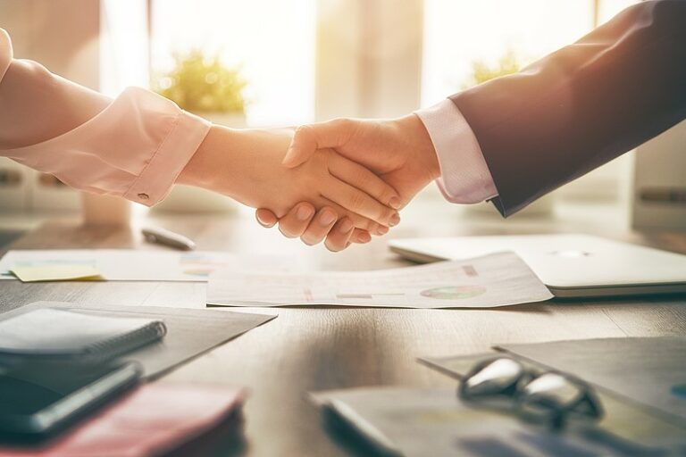 Man and woman shaking hands in office.