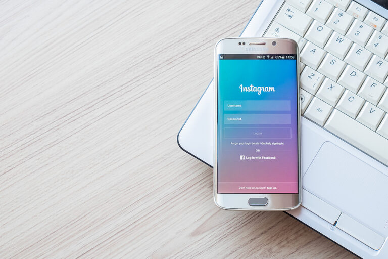 A smart phone resting on top of a white laptop with the Instagram login screen open.