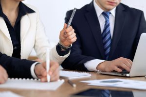 Woman holding up pen to pause conversation during a meeting.