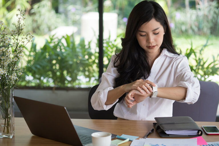 Businesswoman looking at watch in office.