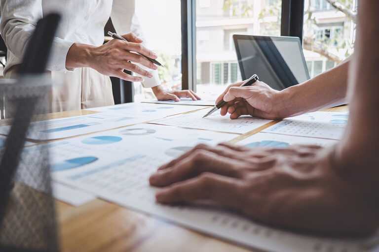 Two marketing agents review printouts of marketing analytics.