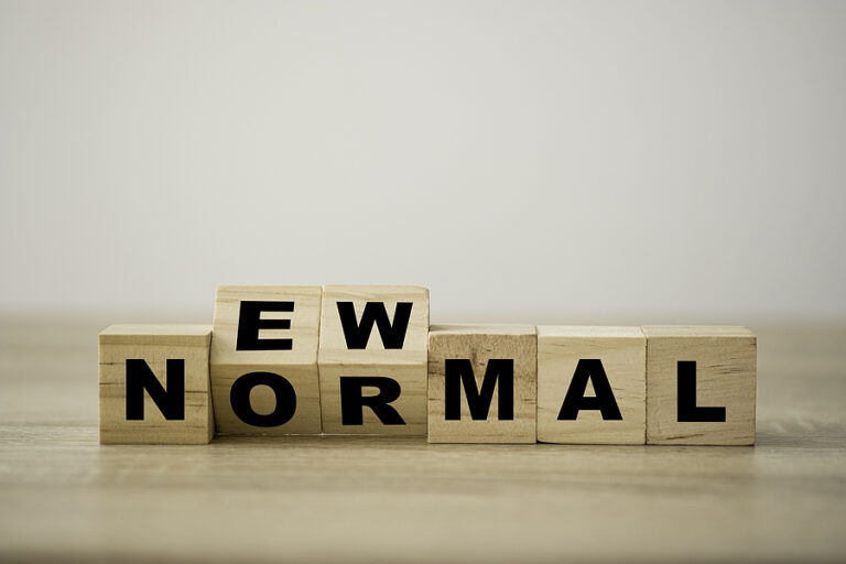 "New Normal" spelled out in wooden blocks on a plain background.