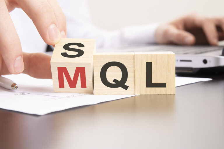 Wooden building blocks on office desk with hand tilting block so both SQL and MQL can be read.