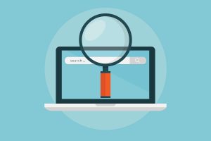 Laptop open with search engine screen and a magnifying glass above it.