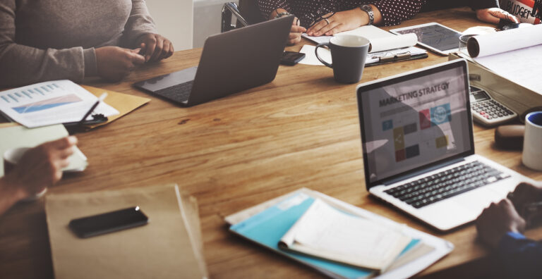 Team of marketers meet at a conference table to discuss marketing strategy.