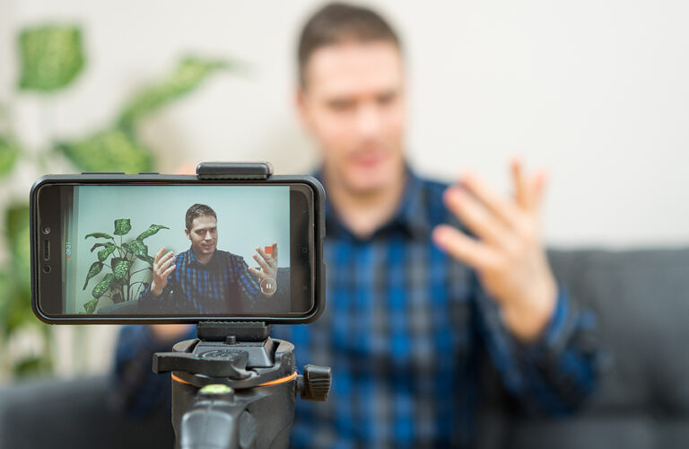 Man gesturing towards a camera while making a video blog.