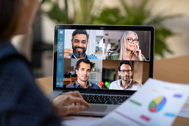 Back view of business woman talking to her coworkers and business partners during a video conference call.