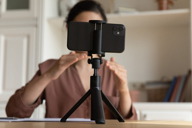 A woman recording an Instagram video in front of a cellphone on a tripod