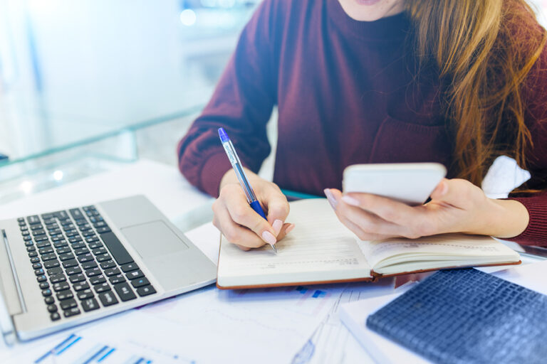 Woman taking notes at computer watching webinar about social media strategy