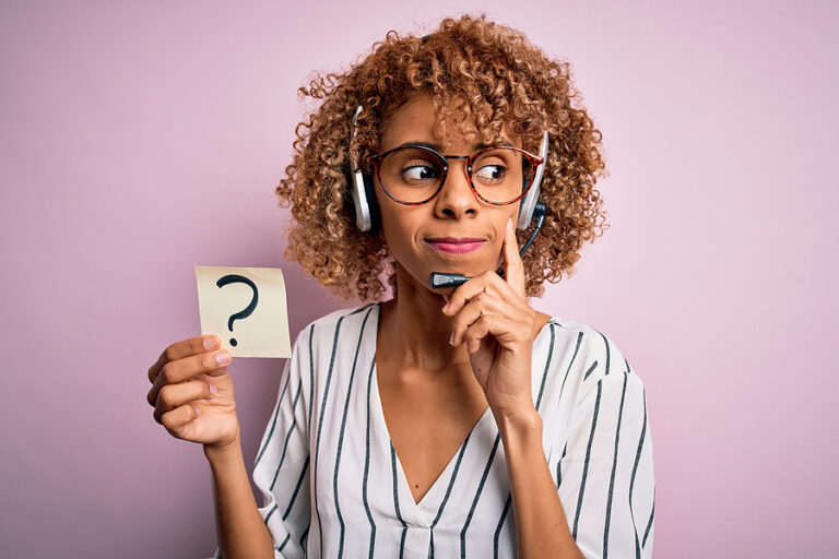 A women wearing a headset holding a post-it note with a question mark on it, indicating the important of asking questions as a professional